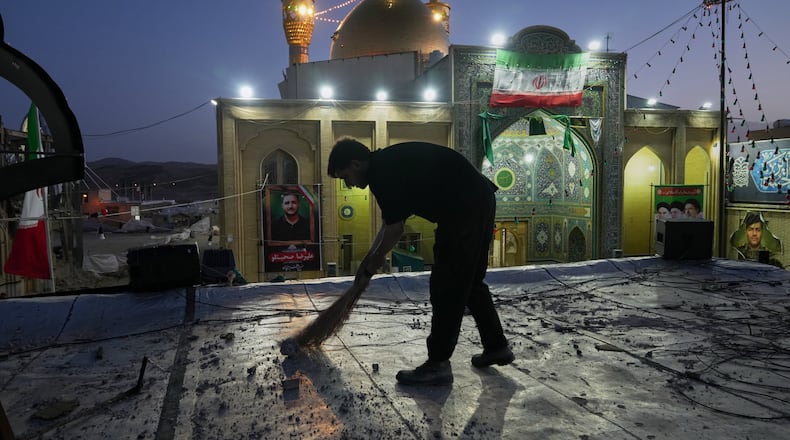 A worker cleans an area within the Grand Hosseiniyeh complex, with the mosque visible in the background, that officials say was hit by U.S.-Israeli airstrikes Tuesday in Zanjan, Iran, Saturday, April 4, 2026. (AP Photo/Francisco Seco)