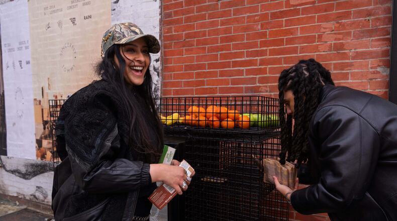Kashish Ali and Elliott McKnight stock a One Love Community Fridge with food, Nov. 15, 2025, in Brooklyn, New York. (AP Photo/Adam Gray)