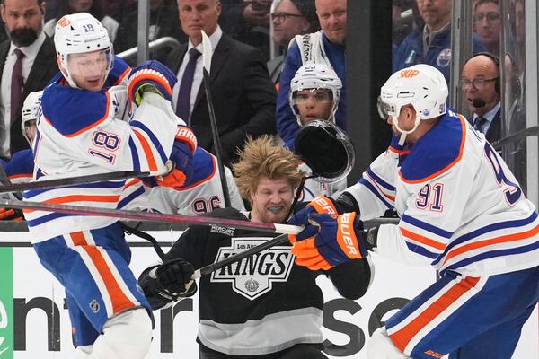 Los Angeles Kings left wing Warren Foegele, center loses his helmet as he is hit by Edmonton Oilers left wing Zach Hyman, left, and left wing Evander Kane during the second period in Game 2 of an NHL hockey first-round playoff series Wednesday, April 23, 2025, in Los Angeles. (AP Photo/Mark J. Terrill)