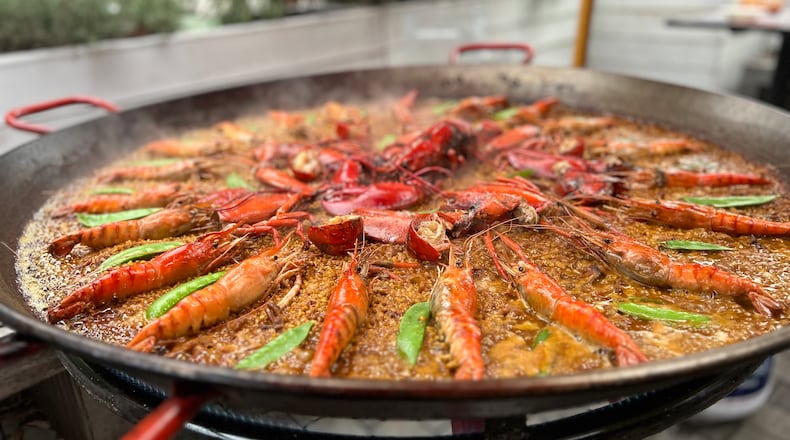 Paella pan filled with rice, shrimp, lobster, and snow peas.