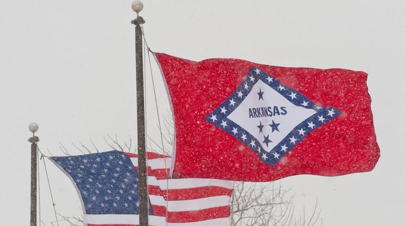 FILE - In this Feb. 1, 2011 file photo, an American and Arkansas flag blow in the wind as snow falls in Fayetteville, Ark. (AP Photo/Beth Hall, File)
