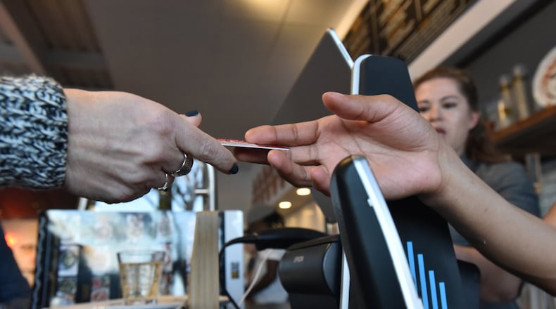Pam Redman hands over her credit card to staffer Daylynn Brown at The Local Pizzaiolo in Atlanta. The restaurant is one of several in the area that don’t accept cash. HYOSUB SHIN / HSHIN@AJC.COM