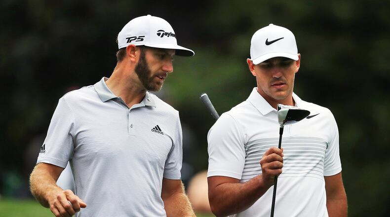 Brooks Koepka checks out the cannon otherwise known as Dustin Johnson’s driver as they stroll the 11th fairway during their Masters practice round early Wednesday. (Curtis Compton/ccompton@ajc.com)