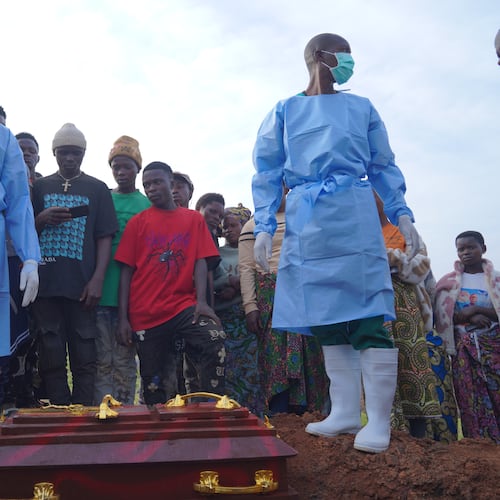 People dressed in protective gear prepare to lower into a grave the coffin containing the remains of 3-year-old Mave Mercienne, who died of Ebola, in Bunia, Ituri province, eastern Congo, Tuesday, Aug. 18, 2026. (AP Photo/Dieudonne Dirole)