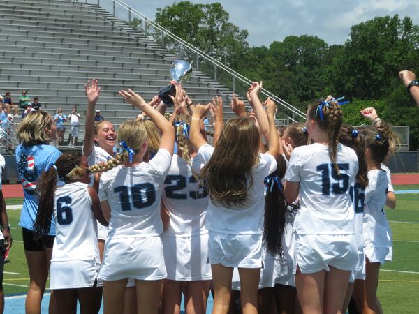 Members of the Cambridge Bears girls lacrosse team celebrate upon receiving the GHSA Division I championship trophy Saturday, May 17, 2025, at Denmark High in Alpharetta. The Bears defeated the Blessed Trinity Titans 17-5 for their second straight state title, and second overall.