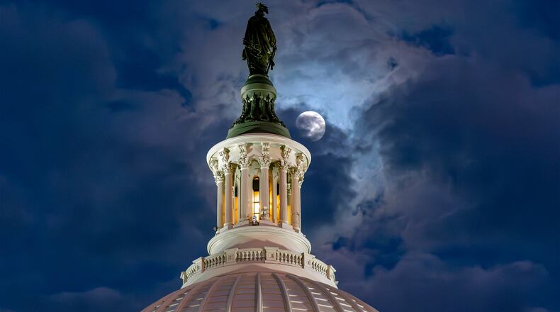 FILE - The moon emerges from the clouds over the U.S. Capitol dome in Washington, Dec. 2, 2025. (AP Photo/J. Scott Applewhite, File)