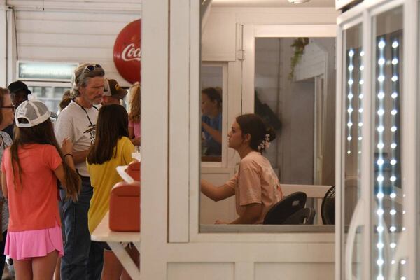 A Dickey Farms employee brings an order of soft serve to shop patrons on Wednesday, July 3, 2024, in Musella, Georgia. Dickey Farms is the oldest, continuously operating peach packinghouse in Georgia and offers tours and sells homemade goods and produce in their shop. (Photo Courtesy of Katie Tucker/The Telegraph)