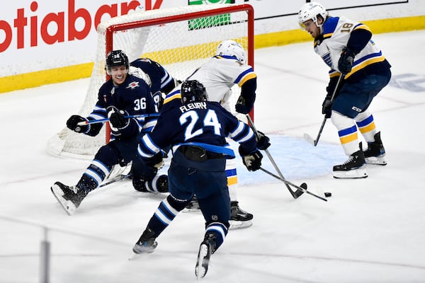 Winnipeg Jets' Morgan Barron (36) and Haydn Fleury (24) defend against St. Louis Blues' Cam Fowler (17) and Robert Thomas (18) in front of Jets goaltender Connor Hellebuyck, second from left, during the second period of Game 7 in an NHL hockey first-round playoff series in Winnipeg, Manitoba, Sunday, May 4, 2025. (Fred Greenslade/The Canadian Press via AP)