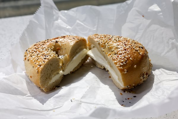 Two halves of an everything bagel filled with an abundant amount of plain cream cheese rests on a paper wrapper from Goldberg's Bagel Company and Deli.