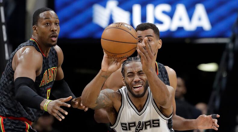 San Antonio Spurs forward Kawhi Leonard (2) tries to work the ball between Atlanta Hawks defenders Dwight Howard (8) and Thabo Sefolosha (25) during the second half of an NBA basketball game, Monday, March 13, 2017, in San Antonio. San Antonio won 107-99.(AP Photo/Eric Gay)