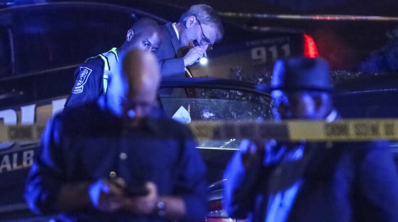 DeKalb County police Sgt. B. Danner (with flashlight) examines the bullet holes in a car where a man was shot and killed early Thursday, Feb. 22, 2018, in DeKalb County. Nicholas Bankston was returning home following his own birthday celebration when he was shot and killed, according to neighbors. His children and two other adults were also in the car, but none were injured. (JOHN SPINK/JSPINK@AJC.COM)