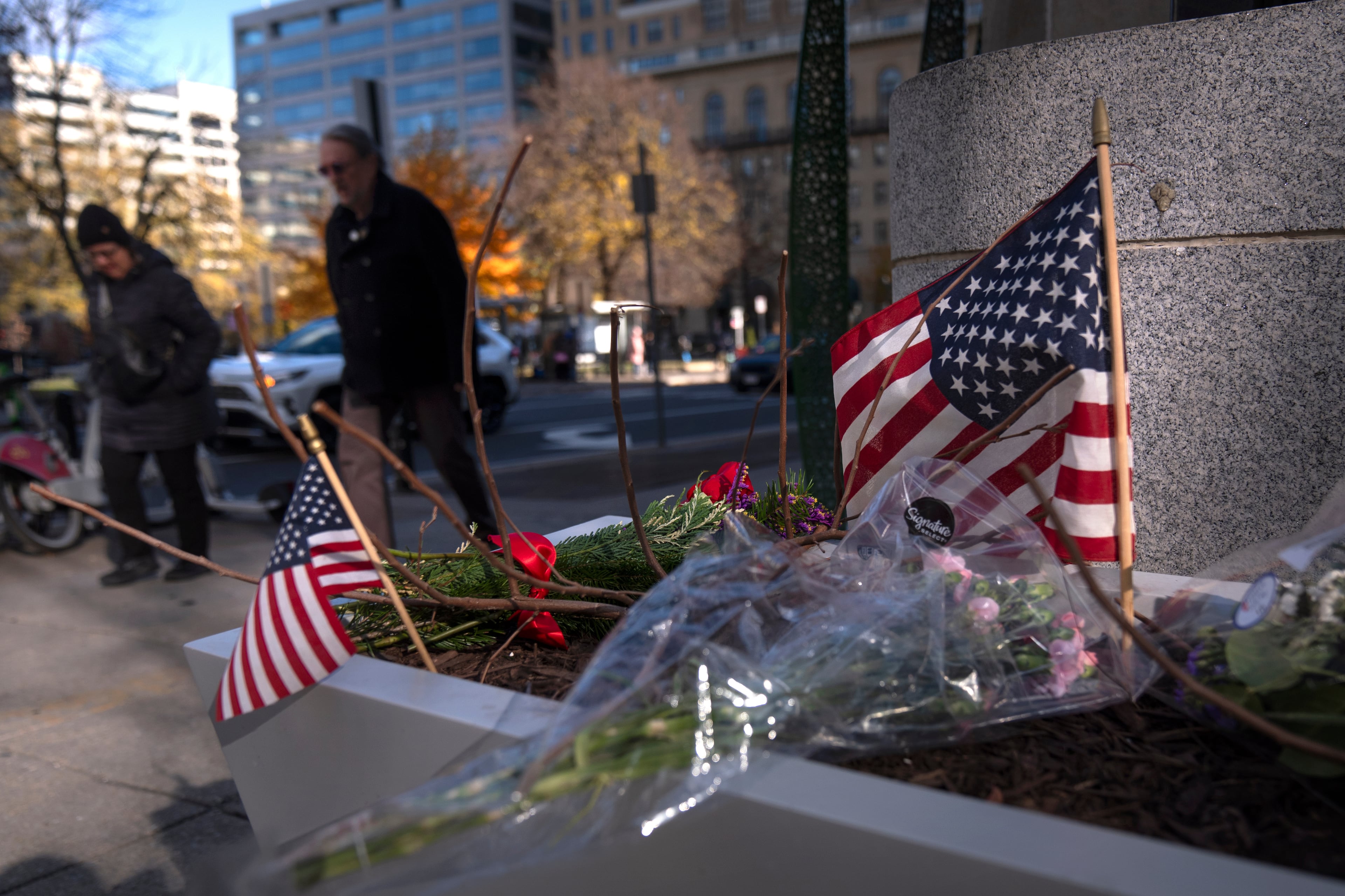 People walk past a small memorial in a planter near the site where two National Guard members were shot last week in Washington. (Mark Schiefelbein/AP)