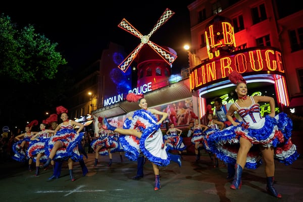FILE - Dancers perform in front of the Moulin Rouge cabaret during the inauguration of the theatre's windmill in Paris, Friday, July 5, 2024. (AP Photo/Thibault Camus, File)