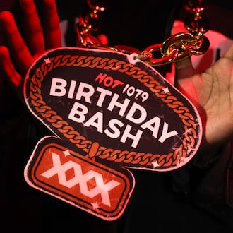An attendee holds up a Birthday Bash pendant on a chain at the Hot 107.9 Who’s Hot showcase at Believe Music Hall in Atlanta on May 21, 2026. The showcase is leading up to the hip-hop station’s 30th Birthday Bash. (Arvin Temkar/AJC)