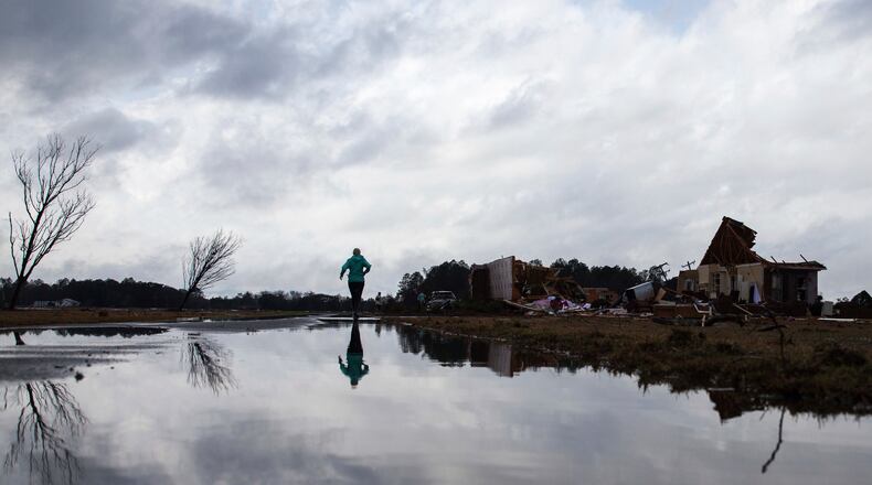 Marilyn Bullard makes her way to a home that was damaged by a tornado, Sunday, Jan. 22, 2017, in Adel, Ga. (AP Photo/Branden Camp)