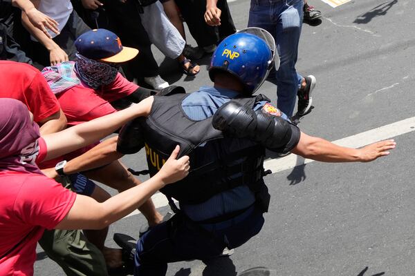 Activists and workers scuffle with a police as they tried to march towards the Malacanang presidential palace during a May Day rally in Manila, Philippines on Thursday, May 1, 2025. (AP Photo/Aaron Favila)