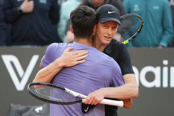 Jannik Sinner of Italy, back, embraces to Carlos Alcaraz of Spain during their final tennis match in the Italian Open at the Foro Italico in Rome, Sunday, May 18, 2025. (AP Photo/Alessandra Tarantino)