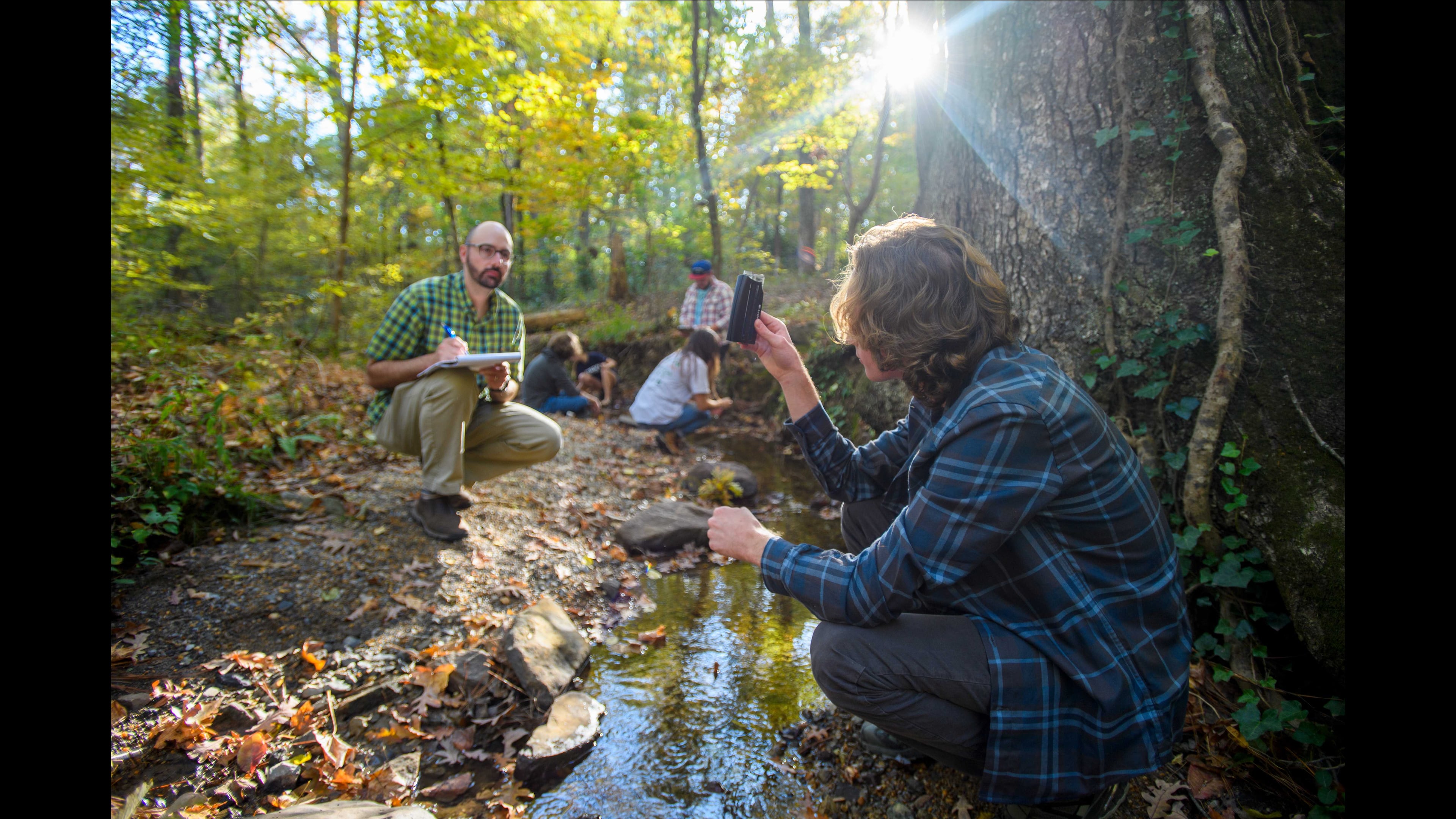 Berry College assistant professor of environmental science Zach Taylor, left, and students take water sample in the stream near the Old Mill. Photo by Brant Sanderlin / Berry College