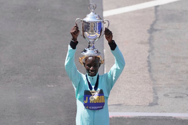 Boston Marathon winner John Korir, of Kenya, hoists the trophy while celebrating after the race, Monday, April 21, 2025, in Boston. (AP Photo/Charles Krupa)