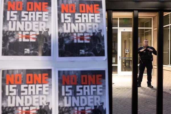 A police officer stands guard as demonstrators protest against Immigration and Customs Enforcement in front of the Atlanta ICE Field Office on Ted Turner Drive on Friday, Jan. 23, 2026. At least 200 people participated. (Arvin Temkar/AJC)