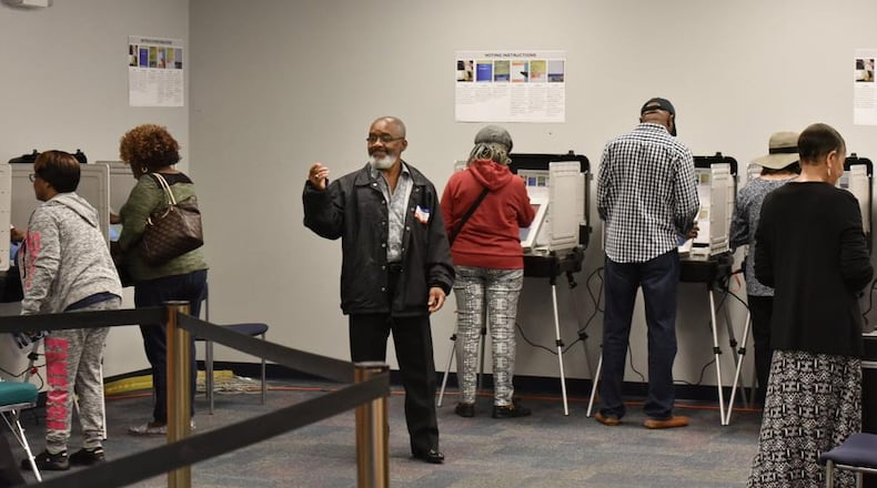 Volunteer Alfred Leblanc (center) directs early voters at the Gwinnett County Voter Registrations and Elections Office in Lawrenceville on Thursday, Oct. 18, 2018.