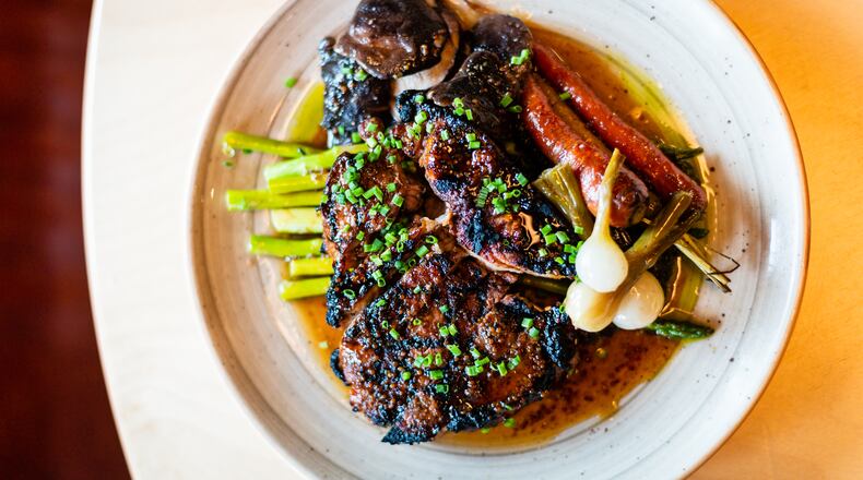The molasses-brined smoked pork chop at Holmes in Alpharetta is a perfectly balanced summer feast on a single plate.