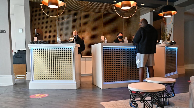 Emily Anderson (behind right) helps a hotel guest from behind the plexiglass divider at the front desk of W Atlanta-Buckhead on Friday, June 12, 2020. The battered hotel industry is gradually recovering, with some hotels in Atlanta reopening but occupancy rates still low. (Hyosub Shin / Hyosub.Shin@ajc.com)