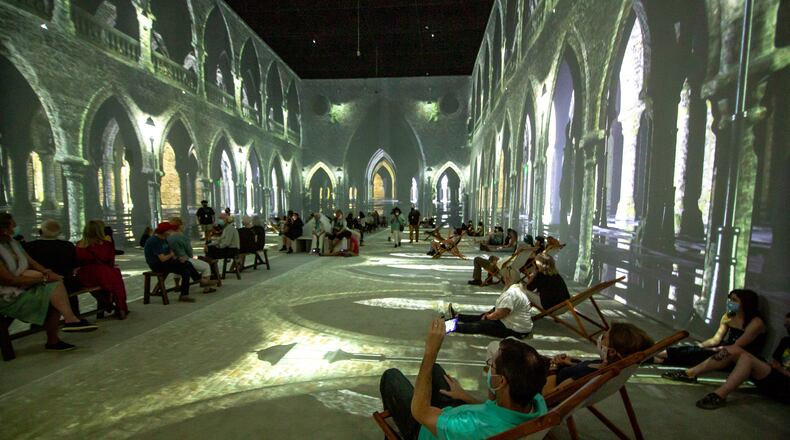 People sit and watch the four-story animated projections during the exhibit, "Van Gogh: The Immersive Experience" at the Pratt-Pullman Yard in Atlanta. STEVE SCHAEFER FOR THE ATLANTA JOURNAL-CONSTITUTION