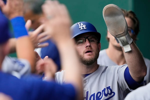 Los Angeles Dodgers' Max Muncy celebrates in the dugout after scoring on a single by Miguel Rojas during the seventh inning of a baseball game against the Kansas City Royals, Sunday, June 29, 2025, in Kansas City, Mo. (AP Photo/Charlie Riedel)