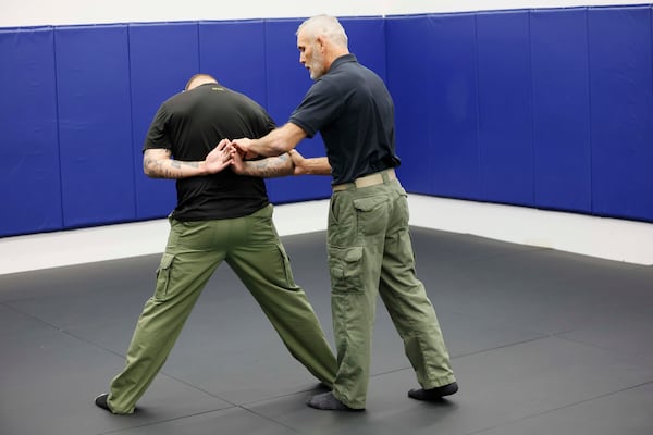 Casey Baynes, who instructs officers in the use of force, demonstrates with Garrett Yates how most arrests occur -- standing up. This is a minimal use of force. (Miguel Martinez/AJC)