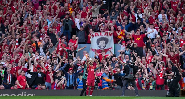 Liverpool's Mohamed Salah takes a selfie with a fans smartphone as he celebrates after scoring his side's fourth goal during the English Premier League soccer match between Liverpool and Tottenham Hotspur at Anfield in Liverpool, England, Sunday, April 27, 2025. (AP Photo/Jon Super)