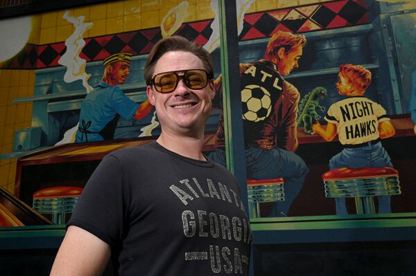 Artist Nick Benson poses for a portrait in front of his mural. He included a self portrait of himself in the style of Norman Rockwell's iconic painting, "The Runaway." (Hyosub Shin/AJC)