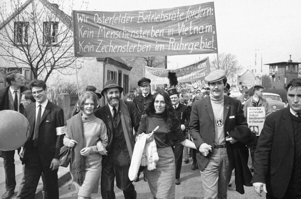 FILE - Joan Baez, center, U.S. folk singer, heads a column of Easter marchers during this years Ban the Bomb campaign in Essen, Germany, April 10, 1966. Marchers carry poster reading "No Dying of Men in Vietnam, No Dying of Coal Mines in the Ruhr District", a protest against the present closure of several coal mines. (AP Photo, File)