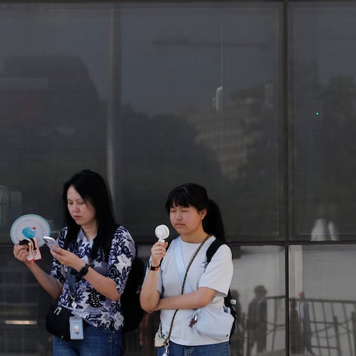FILE - Visitors use fans as as they wait to enter the Washington Monument, July 1, 2026, in Washington. (AP Photo/Tom Brenner, File)