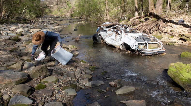 Volunteer Rhett Rutherford bags trash along Proctor Creek during Sweep The Hooch day in Atlanta on Saturday, March 26, 2021. Proctor Creek runs through Atlanta and ultimately empties into the Chattahoochee River. STEVE SCHAEFER FOR THE ATLANTA JOURNAL-CONSTITUTION