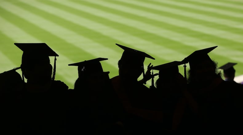 Graduates stand together before the start of commencement exercises for New York University at Yankee Stadium in New York, May 21, 2014. The pay gap between college graduates and everyone else rose to a record high last year, suggesting there are too few graduates. (Michael Appleton/The New York Times)