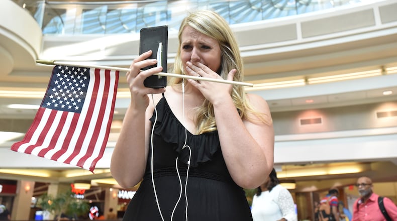 Lindsey Eastwood can’t hide her emotion as she broadcasts livestream video of the flash mob to welcome her husband, Jon Eastwood, at Hartsfield-Jackson International Airport’s domestic terminal atrium on Friday, Aug. 3, 2018. Weather forced a cancellation for Jon’s flight, but he made it in a day later for their in-person reunion. (Photo: HYOSUB SHIN / HSHIN@AJC.COM)