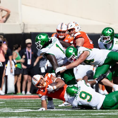 Oklahoma State running back Caleb Hawkins (24) is tackled by Oregon linebacker Devon Jackson (9), linebacker Teitum Tuioti (44) and Bear Alexander in the second half of the NCAA college football game in Stillwater, Okla., Saturday, Sept. 12, 2026. (AP Photo/Mitch Alcala)