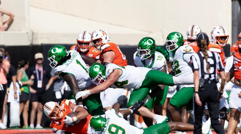 Oklahoma State running back Caleb Hawkins (24) is tackled by Oregon linebacker Devon Jackson (9), linebacker Teitum Tuioti (44) and Bear Alexander in the second half of the NCAA college football game in Stillwater, Okla., Saturday, Sept. 12, 2026. (AP Photo/Mitch Alcala)