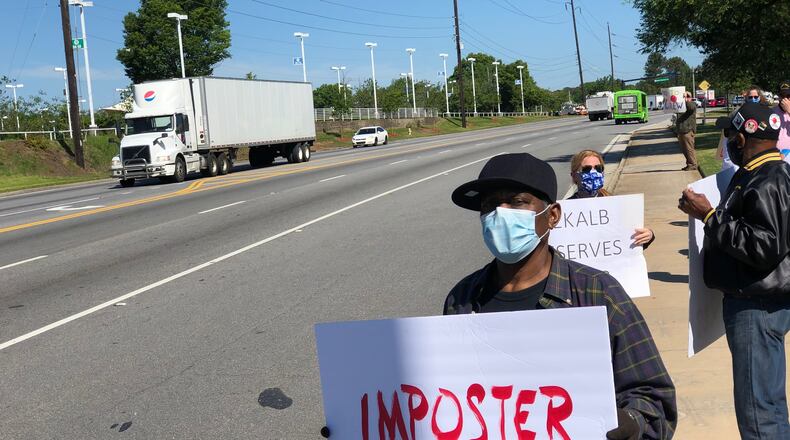 A protester holds a sign that reads "imposter" in red capital letters outside the DeKalb County School District headquarters on Mountain Industrial Boulevard in Stone Mountain on Friday, May 1, 2020. (MARLON A. WALKER/marlon.walker@ajc.com)