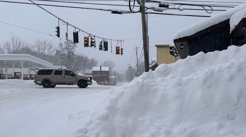 Traffic passes piled-up snow in Lowville, N.Y., Tuesday, Jan. 20, 2026. (AP Photo/Cara Anna)