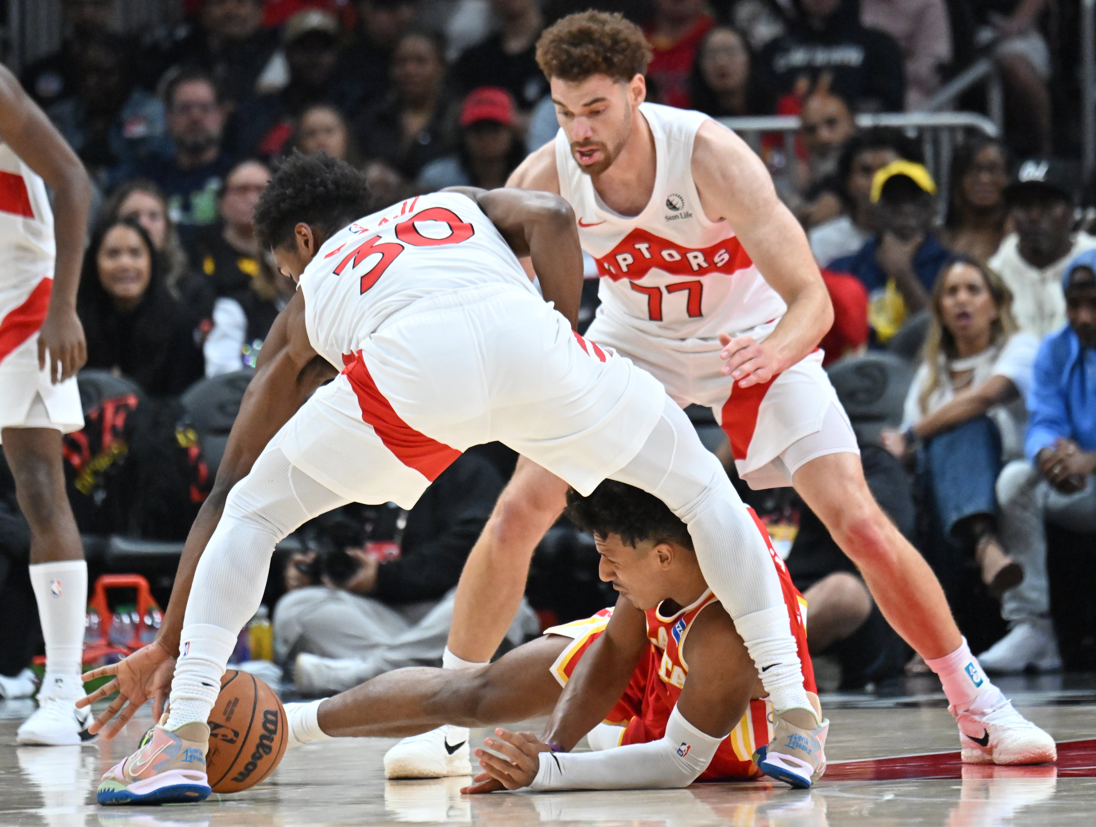 Atlanta Hawks forward Jalen Johnson (1) fights for a loose ball with Toronto Raptors guard Ochai Agbaji (30) during the first half in the home opener at State Farm Arena, Thursday, October 22, 2025, in Atlanta. (Hyosub Shin / AJC)