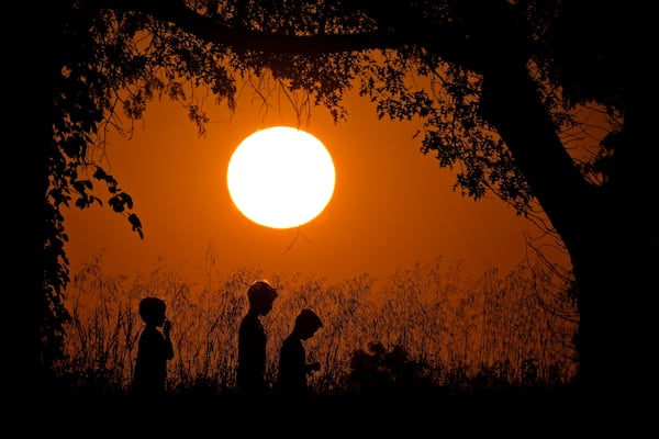 FILE - People are silhouetted against the sky at sunset as they walk at Shawnee Mission park, Sept. 26, 2024, in Shawnee, Kan. (AP Photo/Charlie Riedel, File)