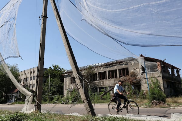 In this photo provided by Ukraine's 65th Mechanized Brigade press service, a local resident rides a bike along the street under an anti-drone net in Orikhiv, Zaporizhzhia region, Ukraine, Tuesday, July 15, 2025. (Andriy Andriyenko/Ukraine's 65th Mechanized Brigade via AP)
