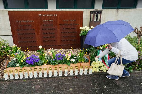 A woman lays a rose during a memorial ceremony in the schoolyard of the Joseph-Koenig high school in Haltern, Germany, ten years after 16 pupils and two teachers of the school died in the Germanwings crash in the French Alps, Monday, March 24, 2025. (AP Photo/Martin Meissner)