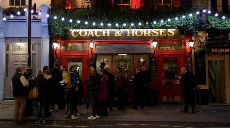 FILE - People stand drinking outside the Coach & Horses pub on Saint Patrick's Day in the Covent Garden district of central London, which is a popular tourist area, Tuesday, March 17, 2020. (AP Photo/Matt Dunham, file)