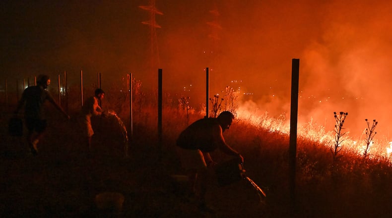 Locals try to extinguish a wildfire on the outskirts of the northern city of Thessaloniki, Greece, Saturday, July 4, 2026. (AP Photo/Giannis Papanikos)