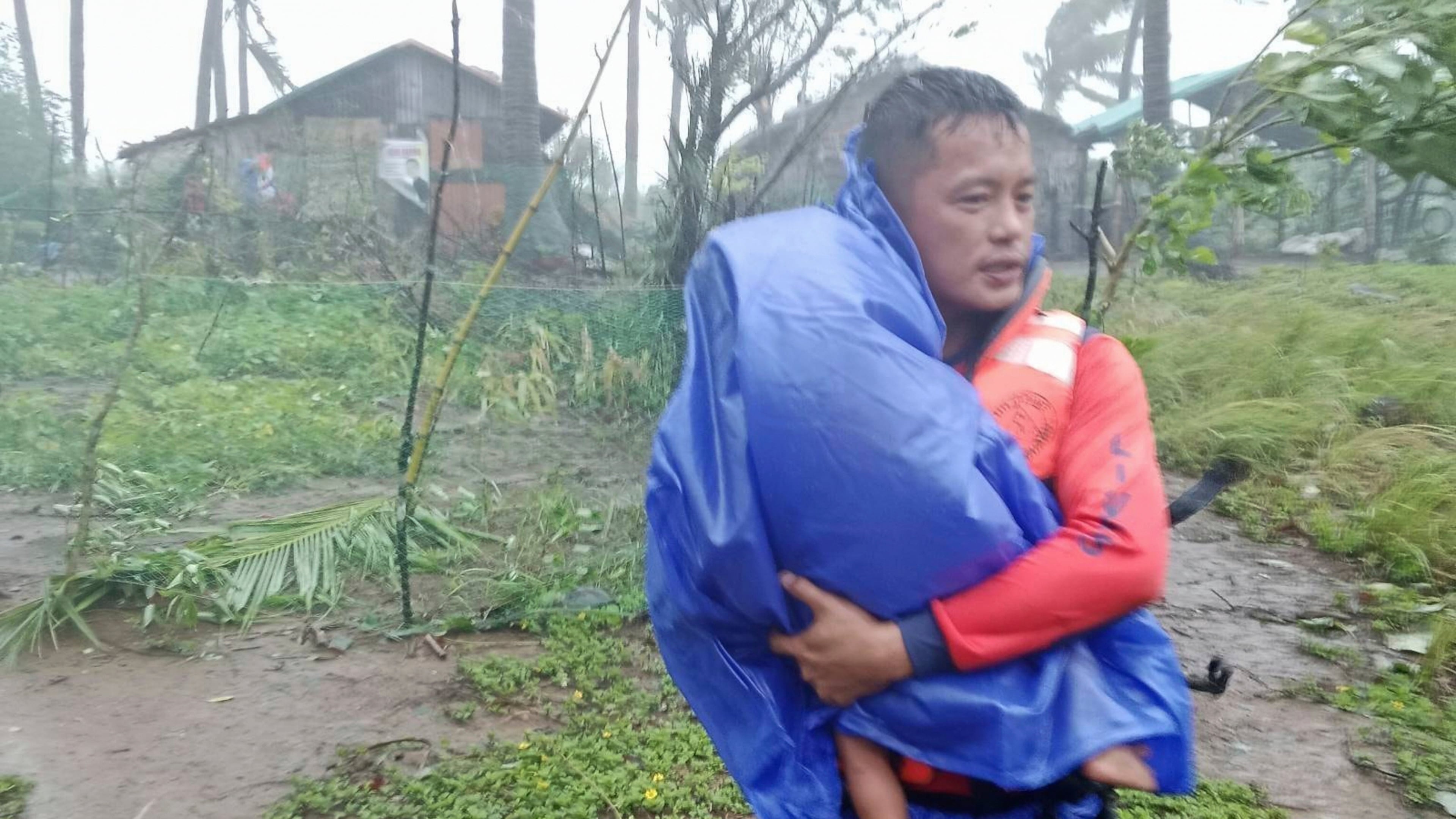 In this photo provided by the Philippine Coast Guard, a rescuer evacuates a child to safer grounds as Super Typhoon Ragasa affects Santa Ana, Cagayan province, northern Philippines, Monday, Sept. 22, 2025. (Philippine Coast Guard via AP)