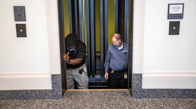 The Office of Insurance and Safety Fire Commissioner Safety Inspector Kenny Leatham, left, and his supervisor Ben Crawford, a chief inspector, right, are working on the annual inspection of elevators at the Nathan Deal Judicial Center on Wednesday, Oct 13, 2021. The control rooms all are checked as well, and require high-voltage certification to enter. (Jenni Girtman for The Atlanta Journal-Constitution)