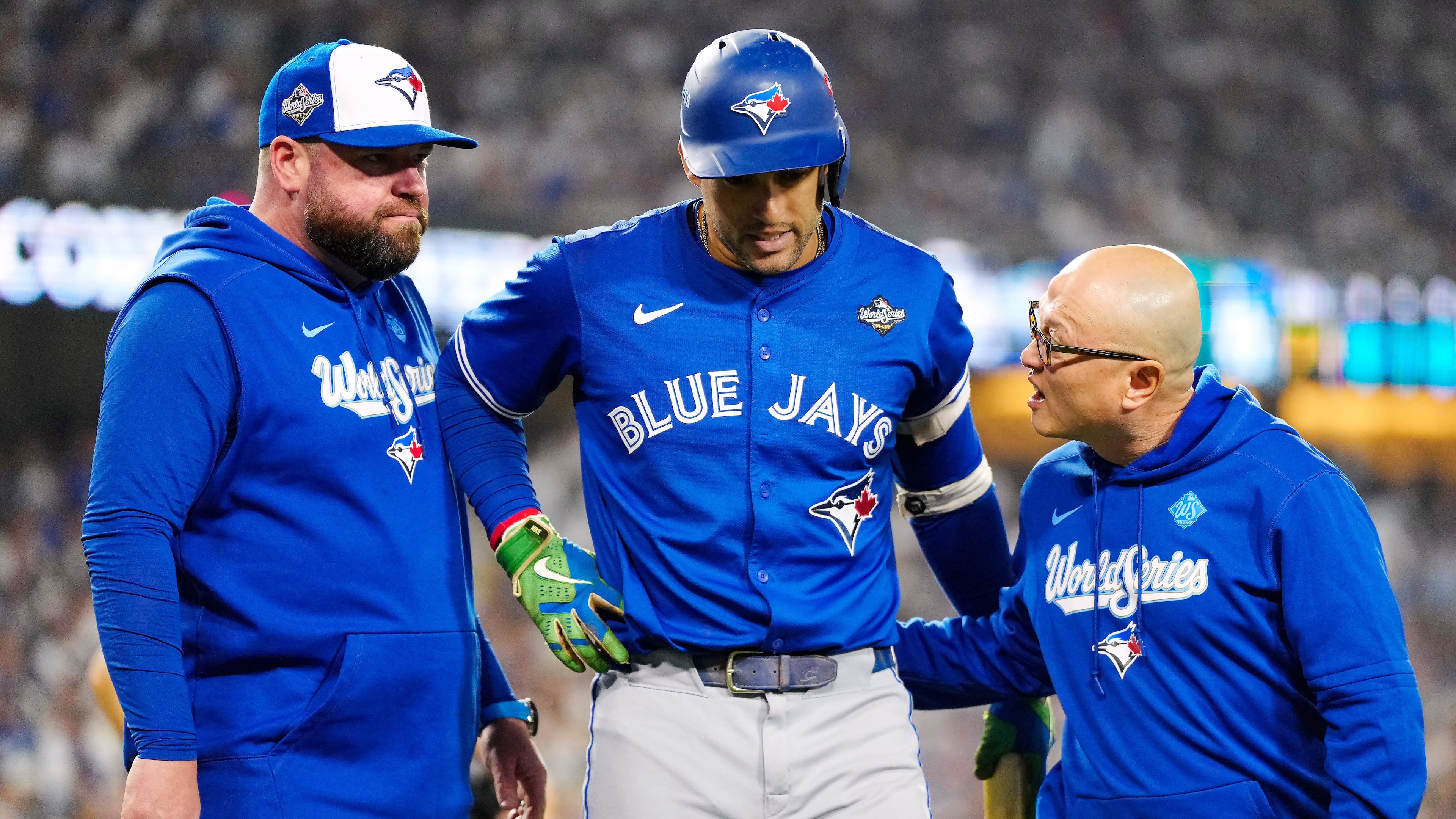 Toronto Blue Jays' George Springer, center, walks off the field as he leaves with an injury with manager John Schneider, left, and first assistant athletic trainer Voon Chong, right, during the seventh inning in Game 3 of baseball's World Series against the Los Angeles Dodgers in Los Angeles, Monday, Oct. 27, 2025. (Frank Gunn/The Canadian Press via AP)